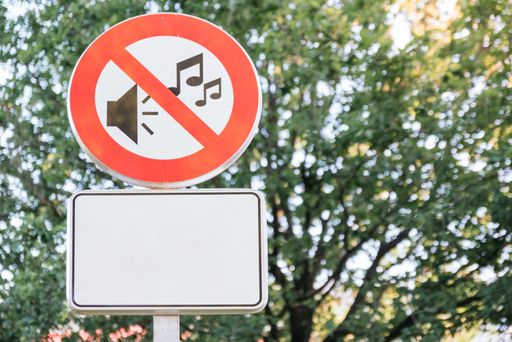 A closeup shot of a "No loud noise" sign under the sunlight in a street