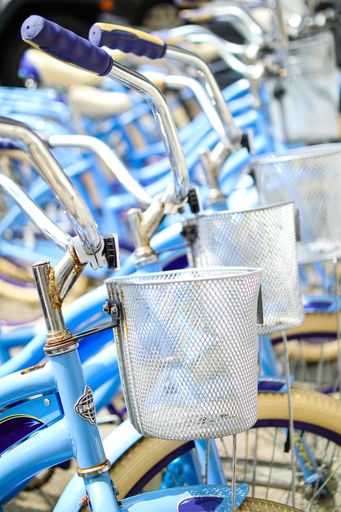 A vertical shot of a row of blue bicycles with silver baskets