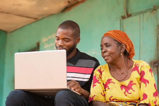 A young black male teaching his older mother how to use technology