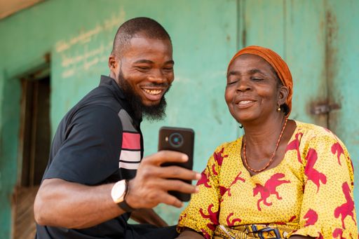 A young black male teaching his older mother how to use technology