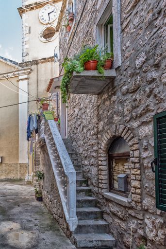 A beautiful view of an old house with potted plants in a village on a sunny day