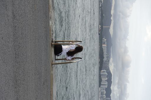 A vertical back view of a girl sitting on the stairs in the sea in Hong Kong, China