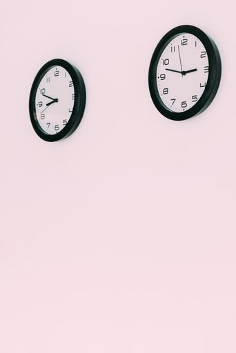 A vertical shot of two clocks hanging from the wall