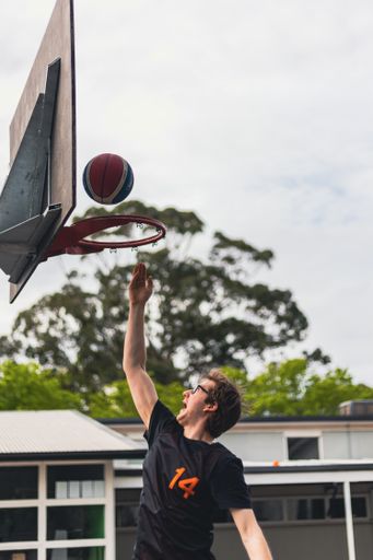 A vertical shot of a basketball player playing basketball outdoors