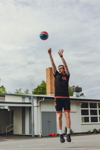 A vertical shot of a basketball player playing basketball outdoors