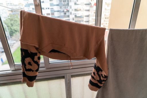 A closeup shot of a sweater and a blanket on a wire over a background of glass windows