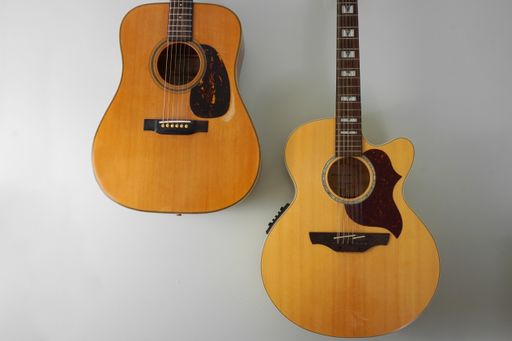 A six string and a twelve string acoustic guitars hanging on a grey wall.  Close-up with copy space