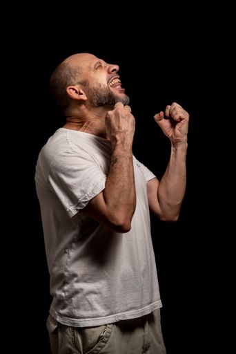 A portrait of an agitated man standing against a black background