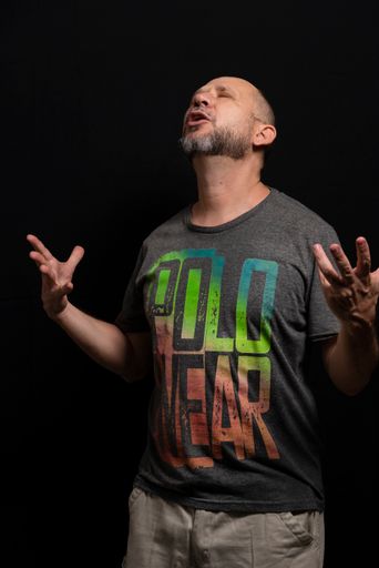 A portrait of an agitated man standing against a black background
