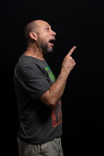 A portrait of an agitated man standing against a black background