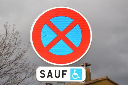 A closeup shot of restricted parking zone sign with the exception of disabled people in France