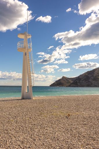 A vertical shot of a white lighthouse on the beach