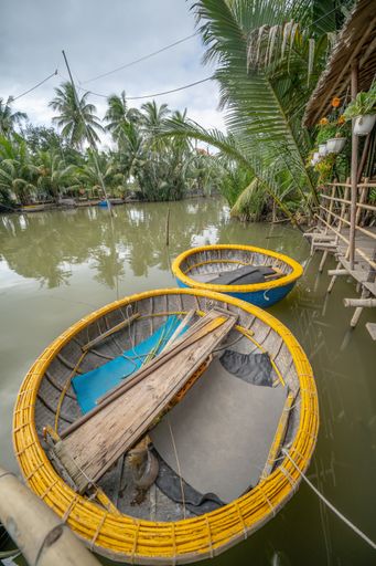 A vertical shot of two Vietnamese round boats in the lake