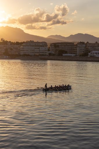 A vertical shot of people on the boat in the lake at dusk