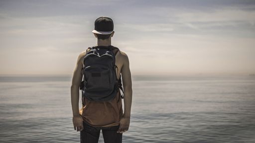 A closeup shot of a young man standing on a beach with overlook to a sea-freedom concept