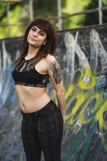 A young attractive Caucasian female with tattoos standing against a  skating ramp