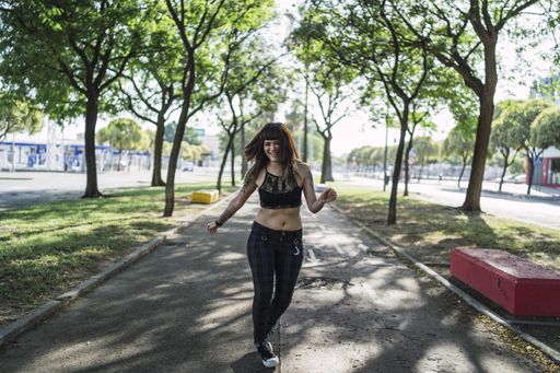 A young attractive Caucasian female with tattoos standing in the park and making a cute face