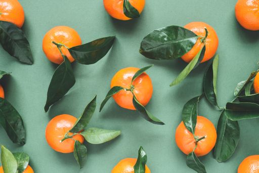 Top view of fresh mandarins with leaves on green background