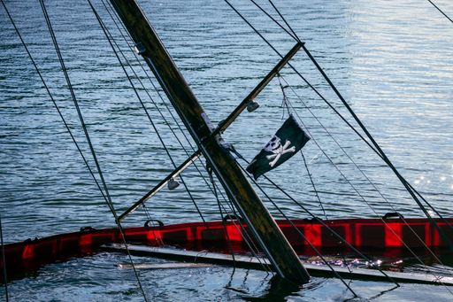 The mast of a sunken boat with a pirate flag sticking up from water