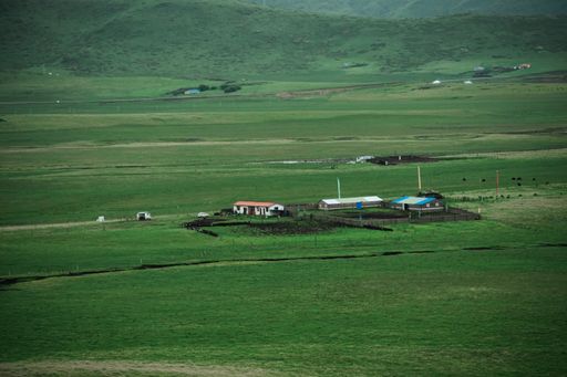 A beautiful shot of farm houses and wooden pens in the middle of green fields in the countryside
