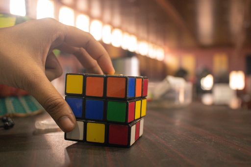A hand holding a Rubik's cube on a wooden table