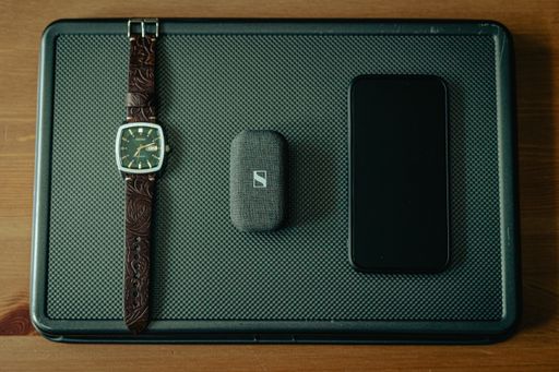 A top view of a Seiko watch, iPhone, and wireless earbuds on display