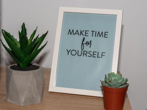 A frame with a quote on a table between succulent plants