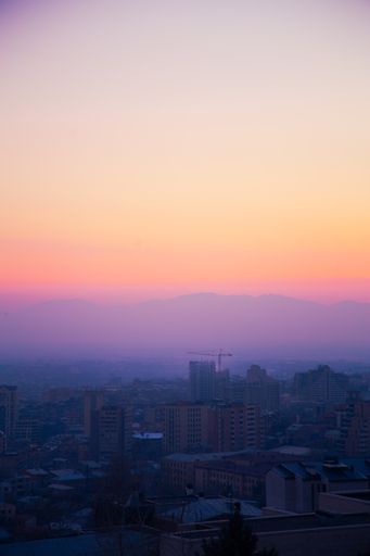 A scenic view from the stairs of Cascade monument to the colorful sunset over roofs of Yerevan city