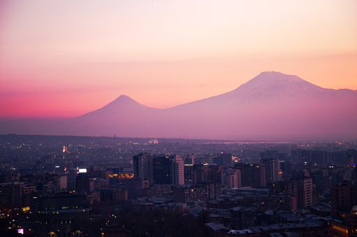 An aerial shot of Mount Ararat and modern buildings at dark in Yerevan, Armenia