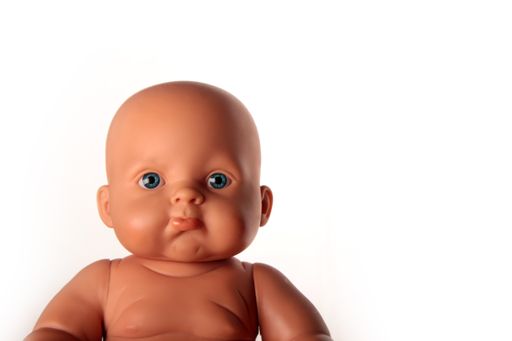 A close up shot of a baby doll with blue ocean eyes isolated in a white background