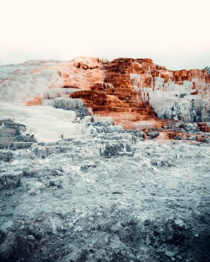 A vertical shot of the mammoth hot springs with sky in the background