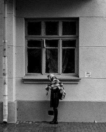 A vertical grayscale shot of a girl standing near an old building in Gomel, Belarus