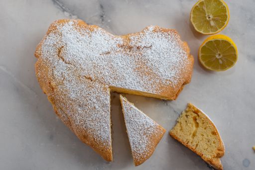 A closeup shot of the heart-shaped lemon cake with slices on a table