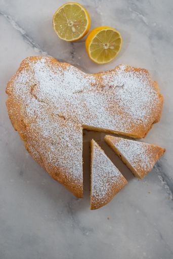 A top view of the heart-shaped lemon cake with slices on a table