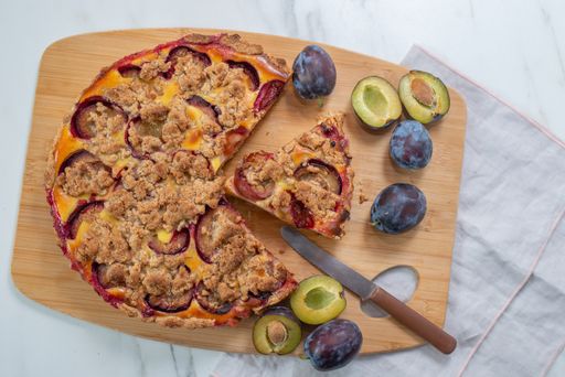 A top view of a sliced homemade plum crumble pie on a table