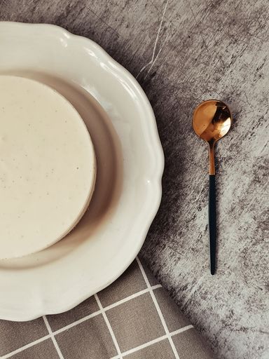 A top view of a delicious homemade cheesecake and a spoon on a table
