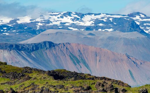 A beautiful shot of mountains partly covered in snow in the daytime.