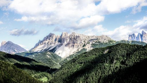 A high angle shot of green and rocky mountain range under the beautiful cloudy sky