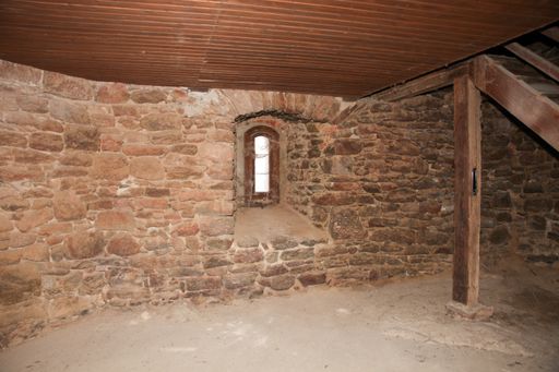 An interior of the ground floor of a private house with brick walls, a window and wooden stairs