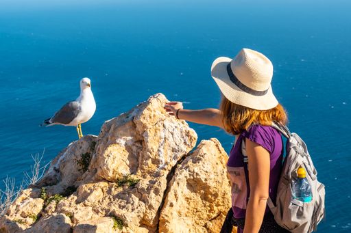 A closeup of a young woman with a seagull at the Mirador de Carabineros in Spain