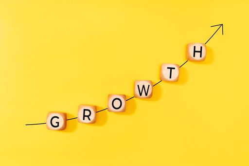 Growth concept. Rising arrow and word on wooden blocks on yellow background. Copy space