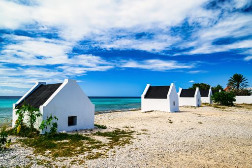 A view of the slave houses on Bonaire in the Caribbean with a blue sky and turquoise sea