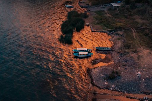 A bird's eye view of boats moored at the rocky shore of blue Lake Atitlan in Guatemala at sunset