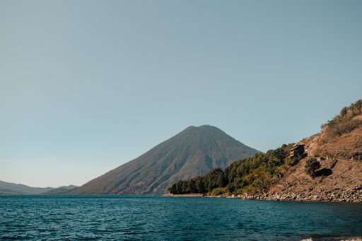 A scenic view of a mountain range against the blue Lake Atitlan in Guatemala