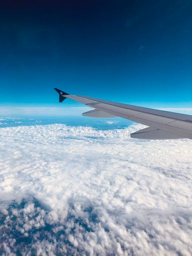 A vertical shot of the airplane winglet against the background of blue sky and white clouds.