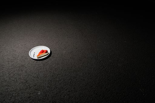 A slice of yummy strawberry cake on a white plate on a black surface