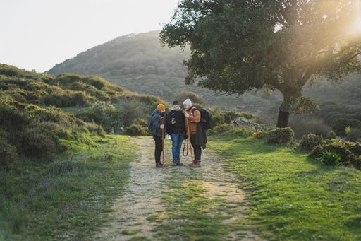 Three men talking and taking a photo on the path of the green route through the peak of  La sierra, Andaluza