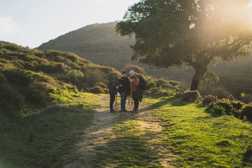 Three men talking and taking a photo on the path of the green route through the peak of  La sierra, Andaluza