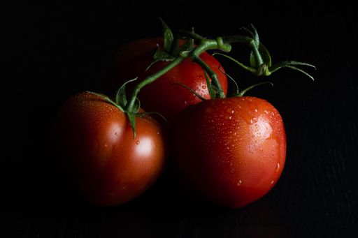 A closeup shot of three red tomatoes with black background