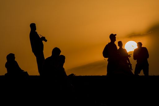 A horizontal shot of silhouetted people during the sunset